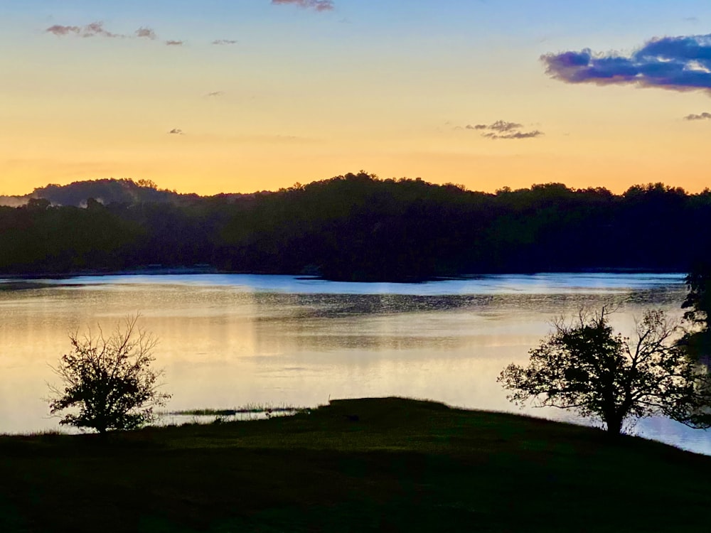 a lake surrounded by trees at sunset