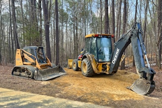 a tractor and a bulldozer are parked on a dirt road