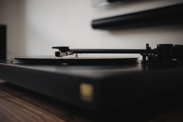 Close-up of hands pressing play on a vintage record player.