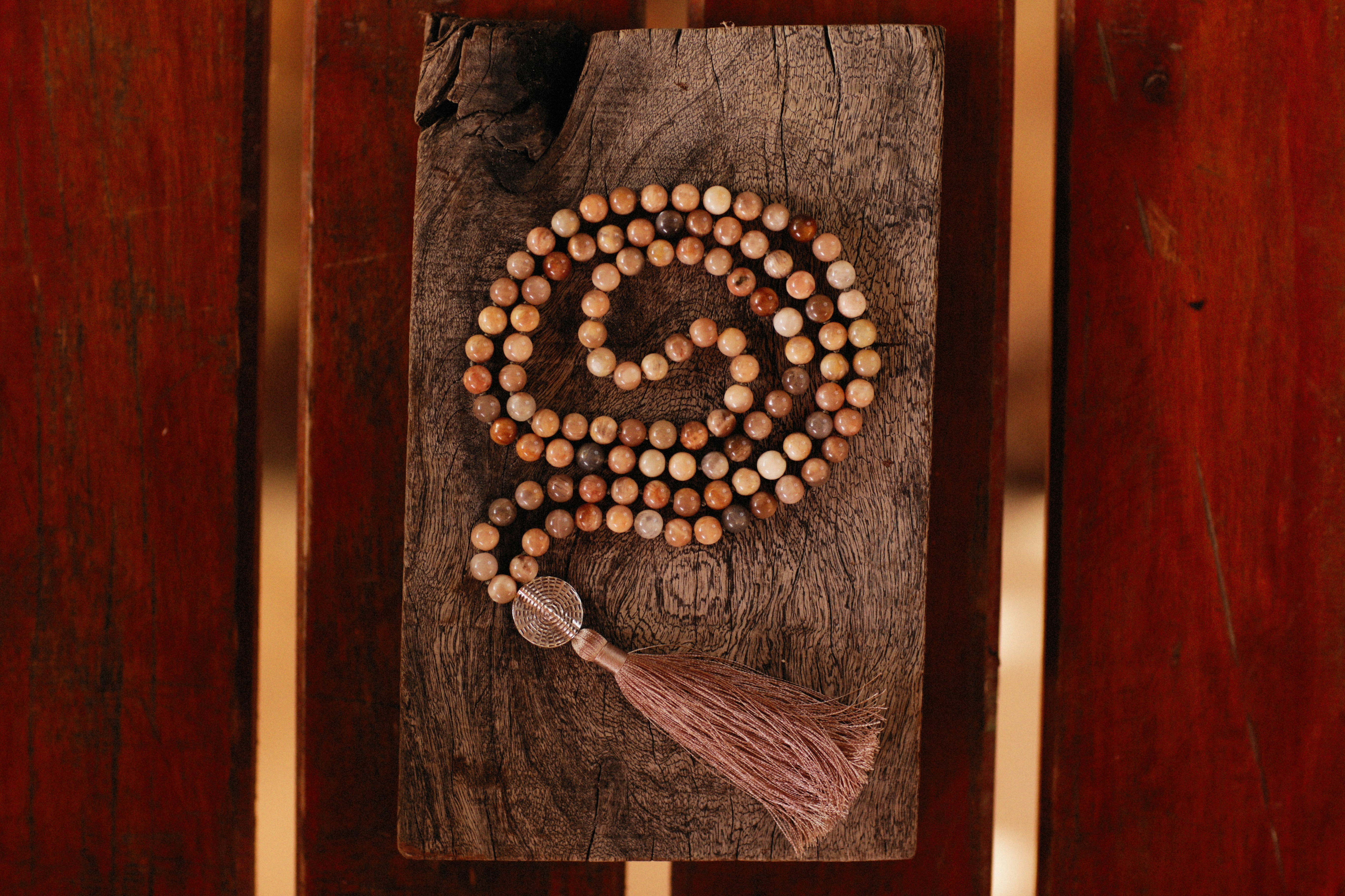 a wooden beaded necklace with a tassel on a piece of wood