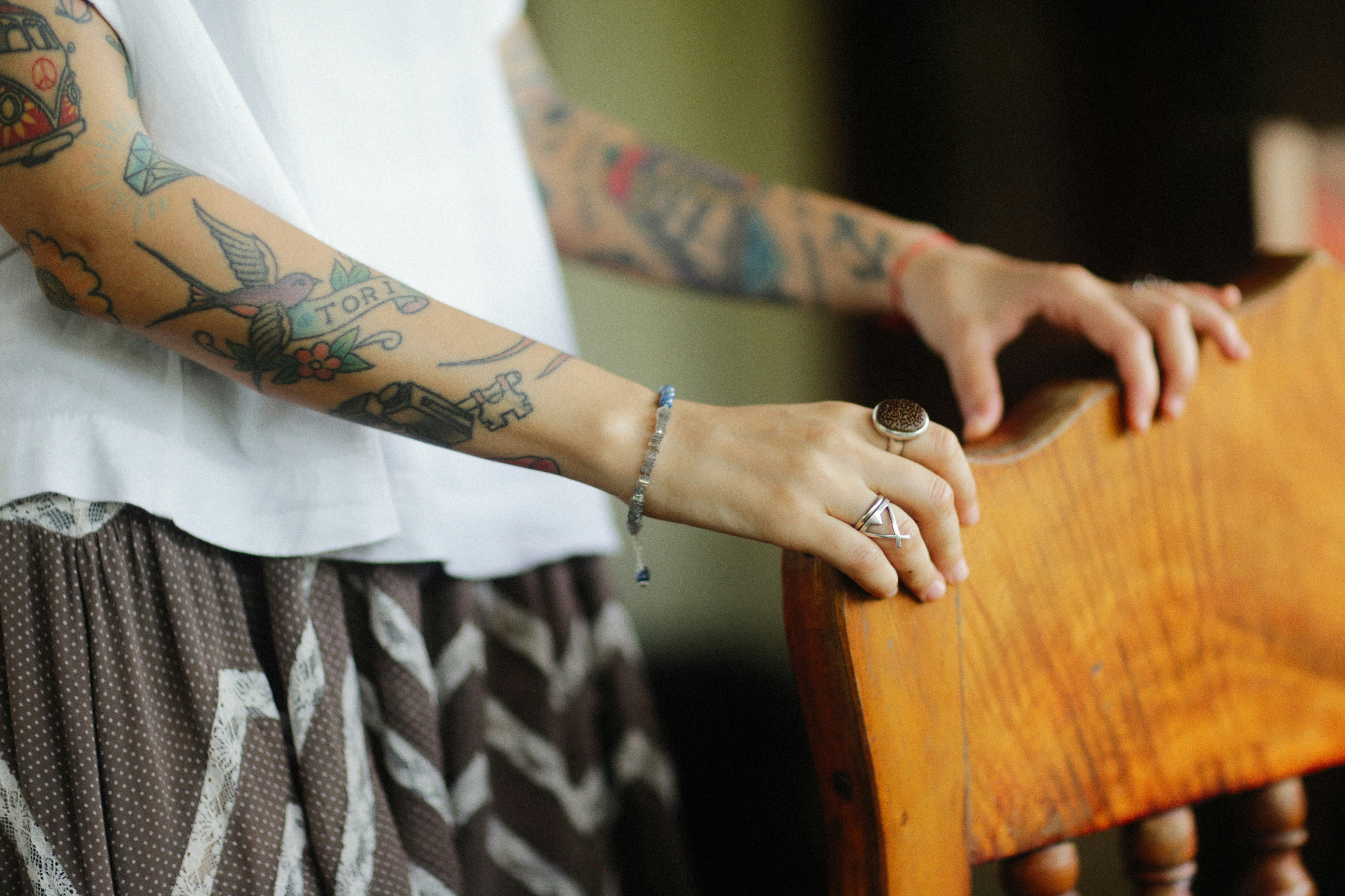 a woman with tattoos on her arm holding a wooden chair