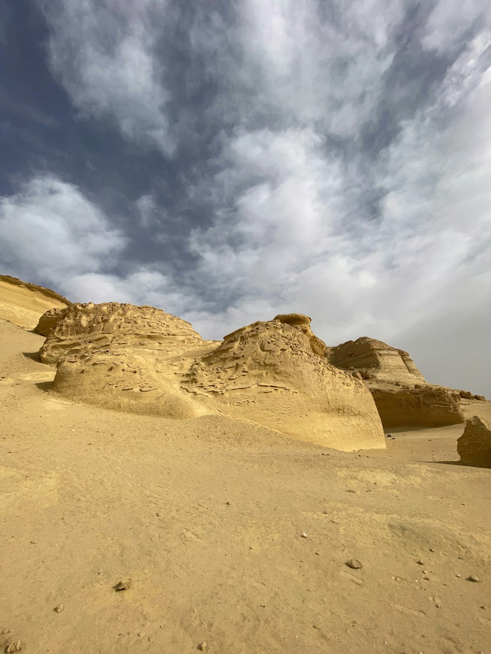 a desert landscape with sand and rocks under a cloudy sky