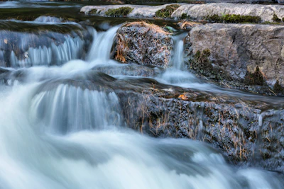 a stream of water running over rocks into a river