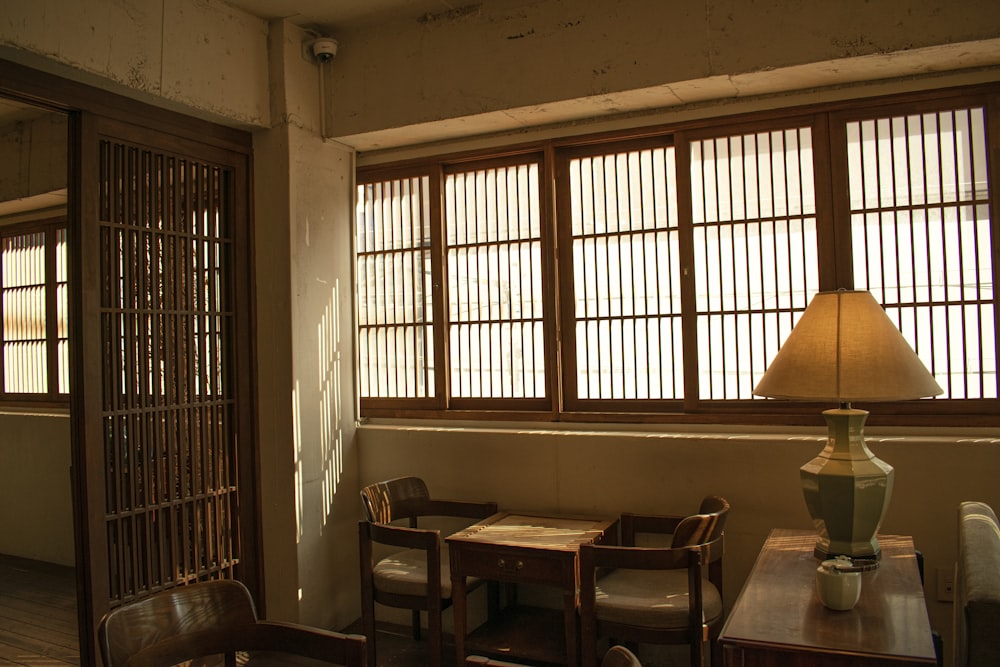 a room with a table, chairs and a lamp