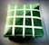 A square package is wrapped meticulously with green leaves and secured with thin white strips woven in a crisscross pattern. The package is placed on a tiled surface, presenting a neat and traditional appearance.