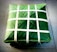 A square package is wrapped meticulously with green leaves and secured with thin white strips woven in a crisscross pattern. The package is placed on a tiled surface, presenting a neat and traditional appearance.