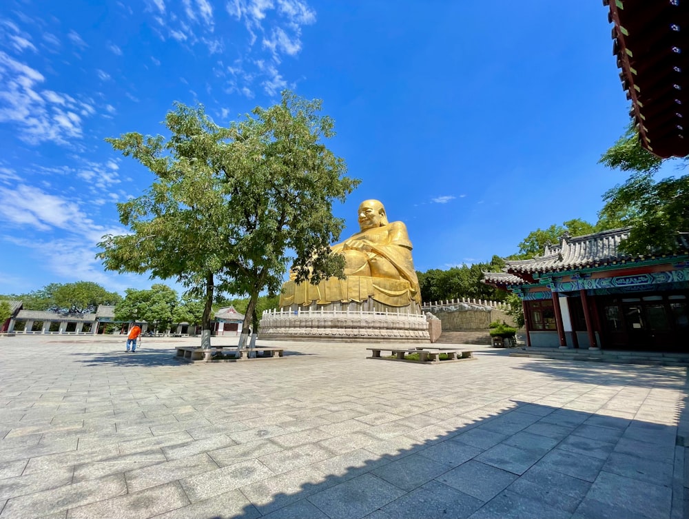 a large golden buddha statue sitting in the middle of a park