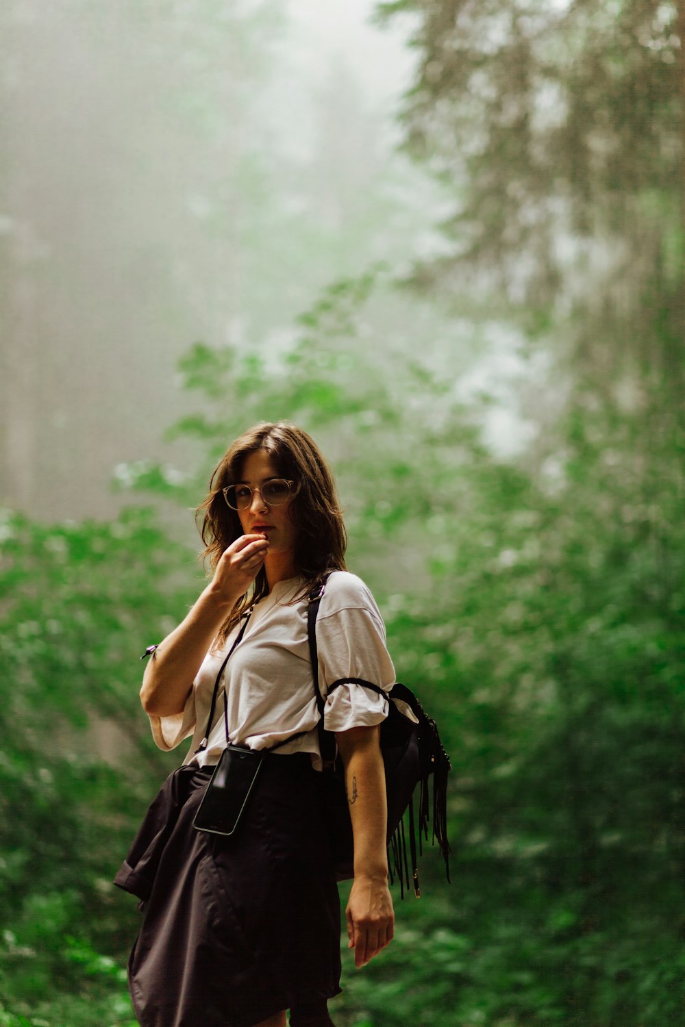 a woman walking through a forest while talking on a cell phone