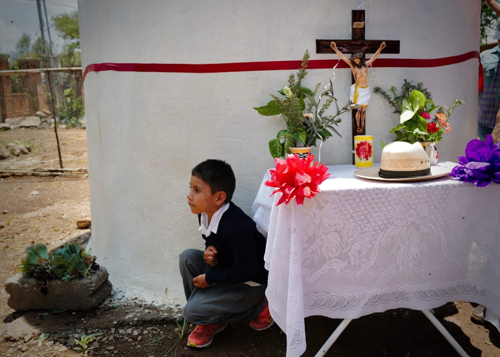 a little boy kneeling down in front of a table with a cake on it