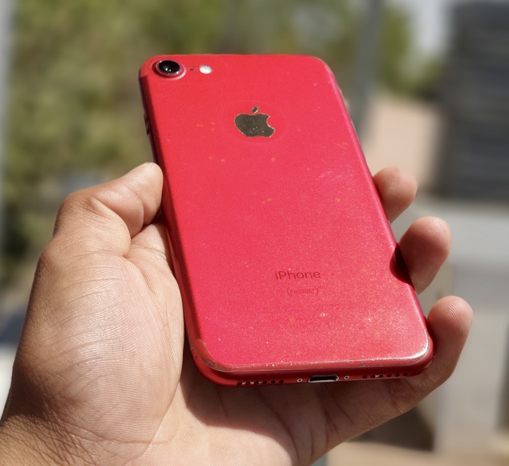 a person holding a red iphone in their hand