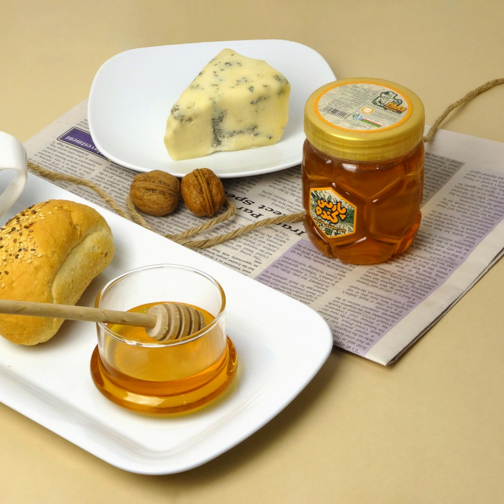 a table topped with plates of food and a jar of honey