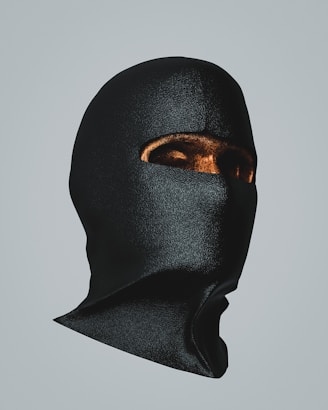 Shadowed image of sleek black masks with metallic details resting on a dark velvet cloth.