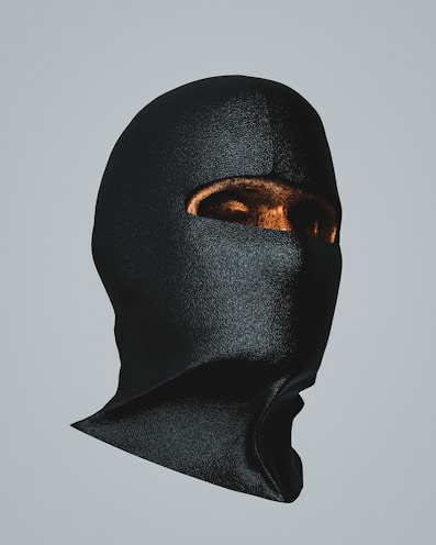 Shadowed image of sleek black masks with metallic details resting on a dark velvet cloth.