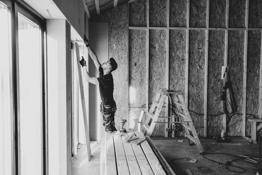 a black and white photo of a man working on a wall