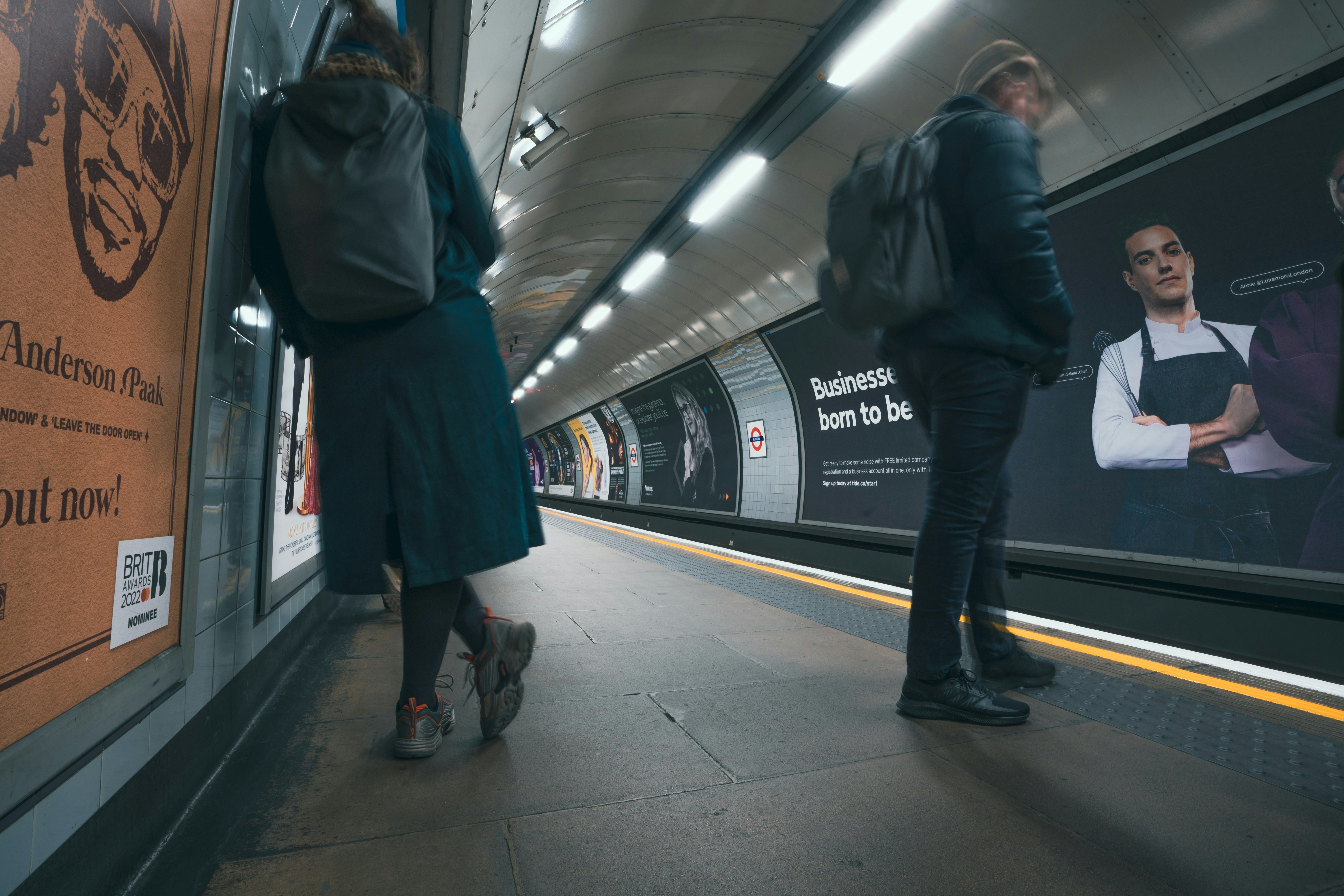 a couple of people standing on a subway platform
