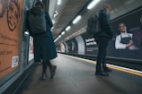 a couple of people standing on a subway platform