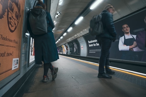 a couple of people standing on a subway platform