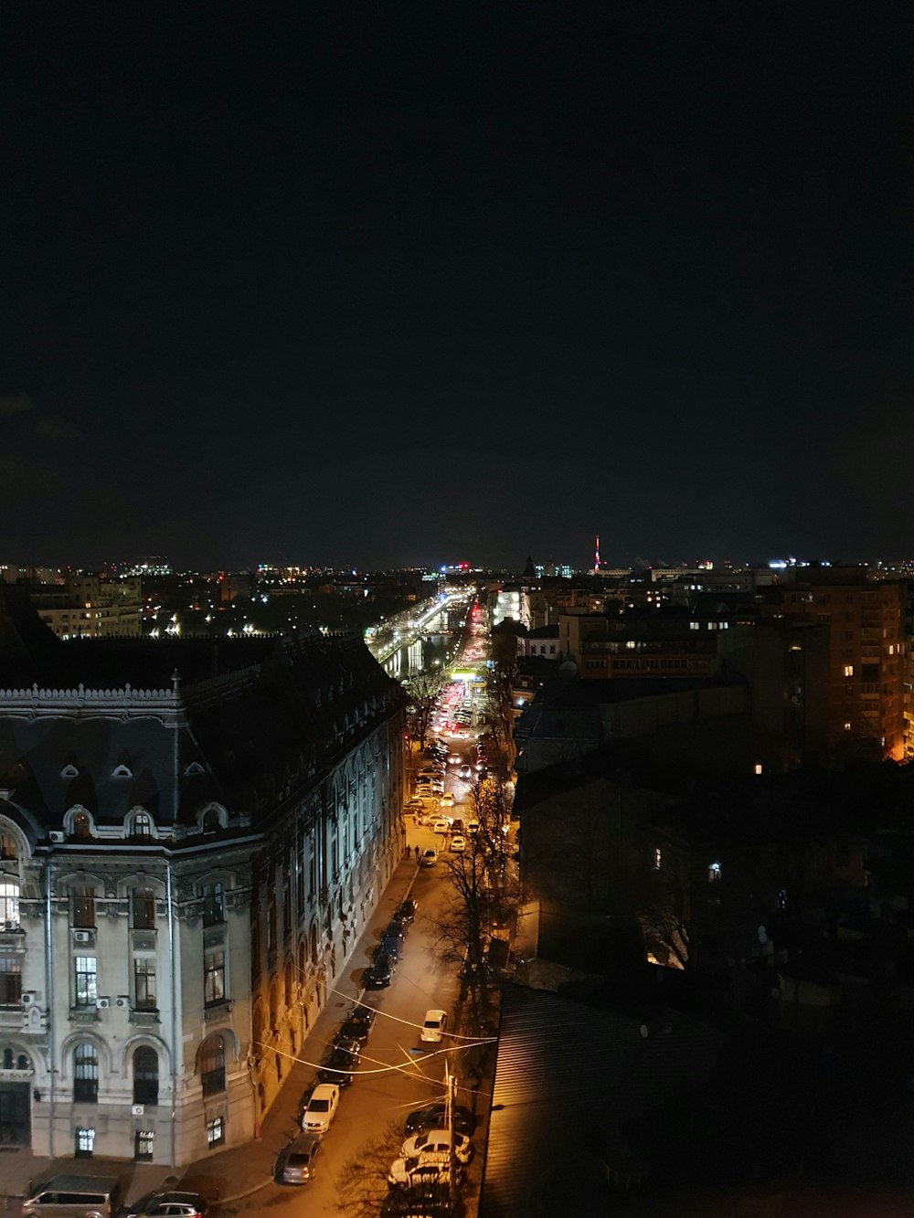 a night view of a city street with a clock tower in the background