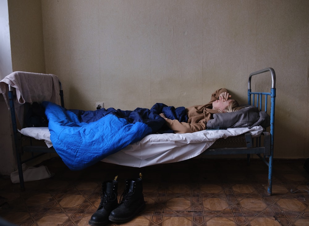 a person laying on a bed with a blue blanket