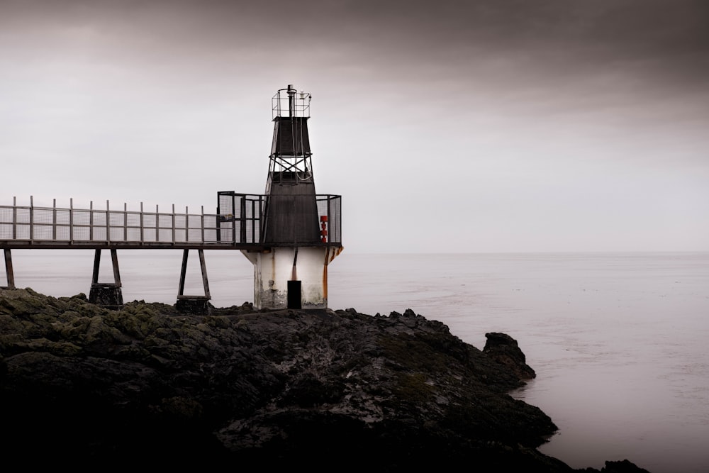 a lighthouse sitting on top of a rocky cliff next to the ocean