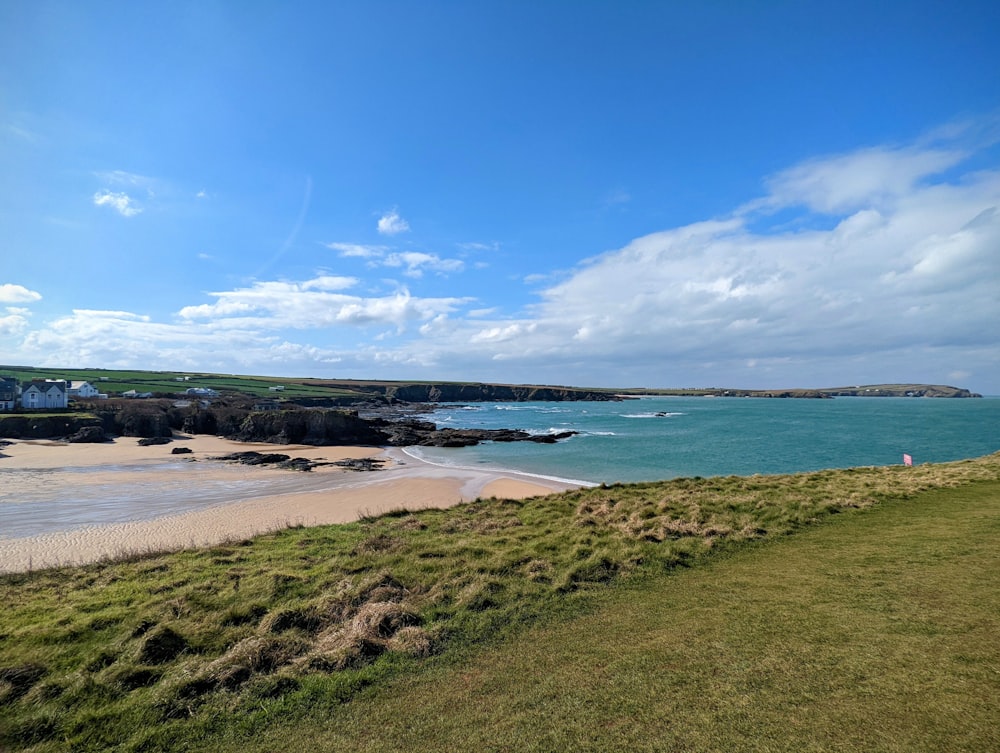 a sandy beach next to the ocean under a blue sky