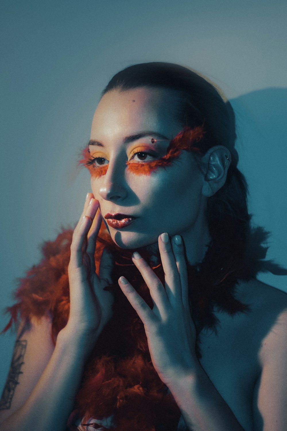 a woman with orange makeup and feathers on her face