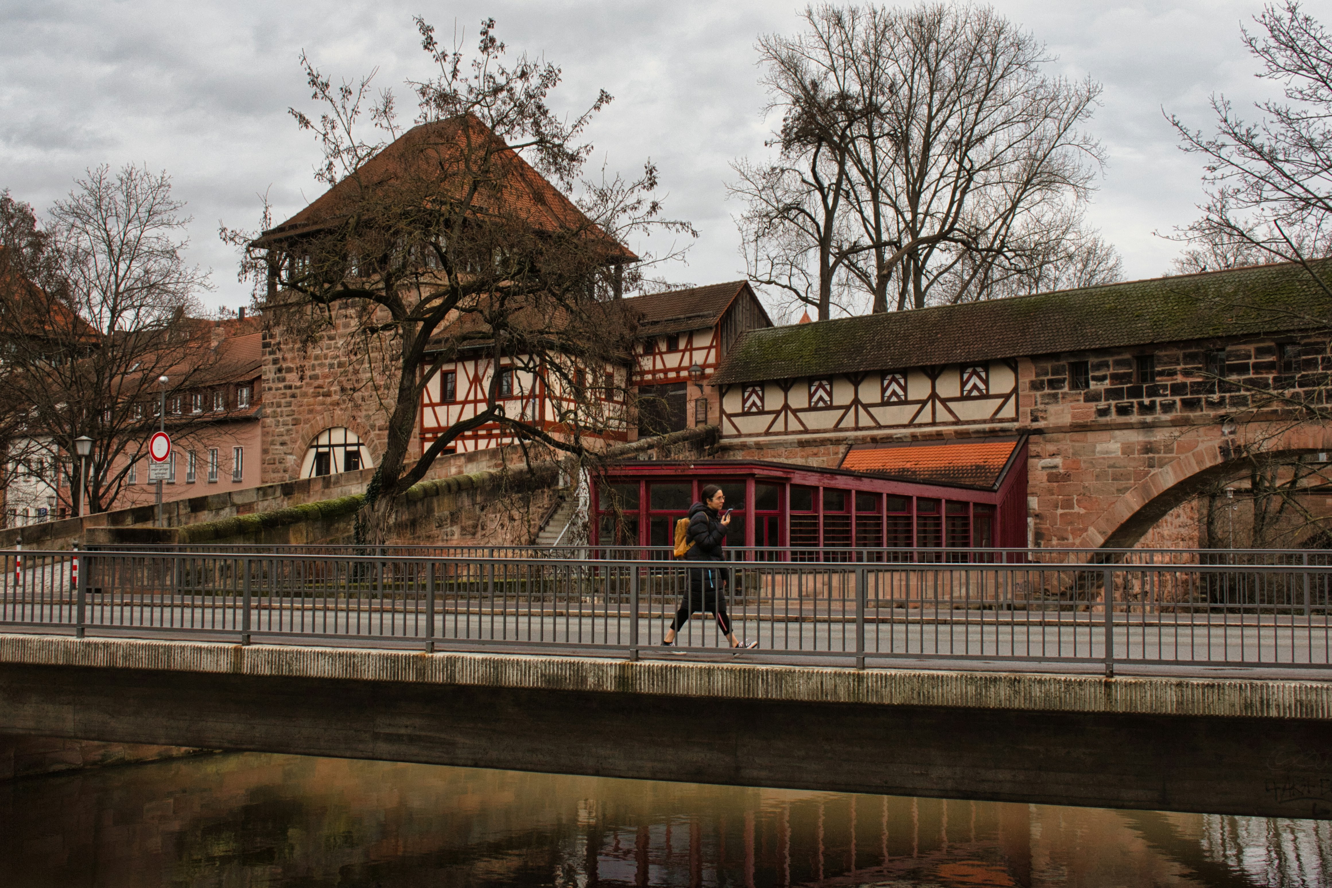 a man walking across a bridge over a river