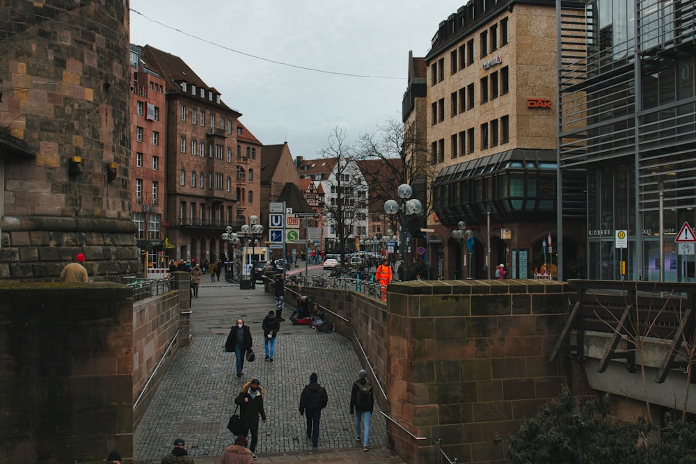 a group of people walking down a street next to tall buildings