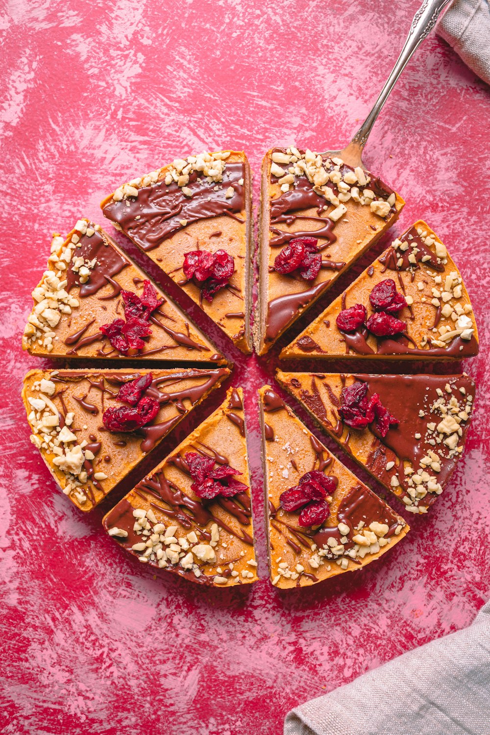 a cake with chocolate and nuts on a pink surface