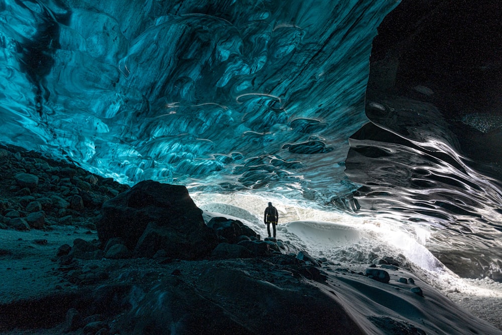 a man standing inside of a blue ice cave