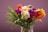 A vibrant bouquet of mixed flowers including roses and tulips in a rustic vase.