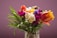 A vibrant bouquet of mixed flowers including roses and tulips in a rustic vase.