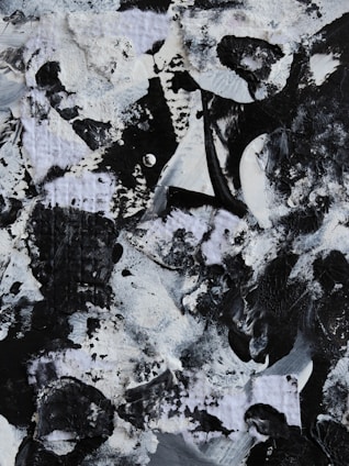 An abstract art piece composed of a variety of textures with prominent black and white paint strokes. The painting features rough, swirling patterns and layered surfaces.