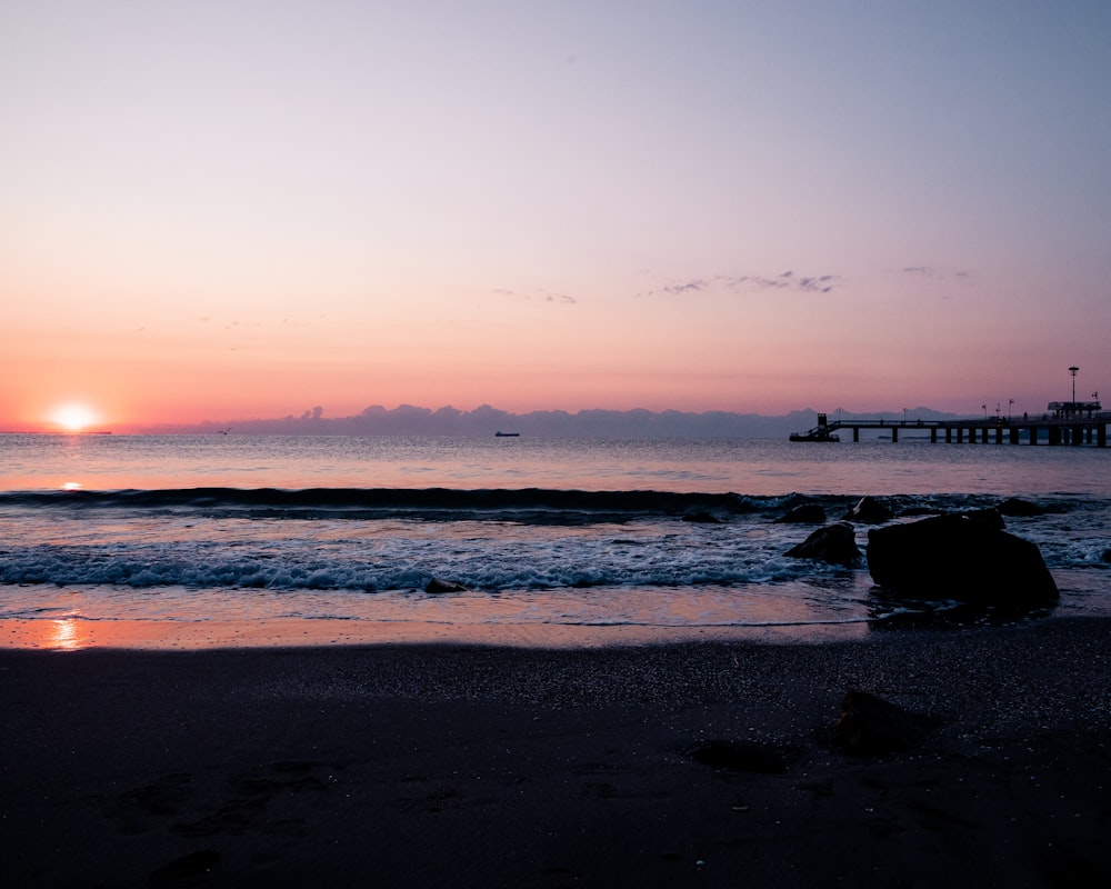 Una puesta de sol sobre el océano con un muelle en la distancia
