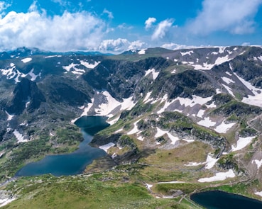 an aerial view of a mountain range with a lake in the foreground