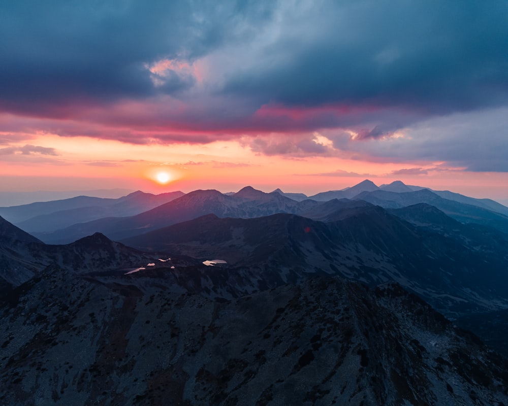 the sun is setting over a mountain range