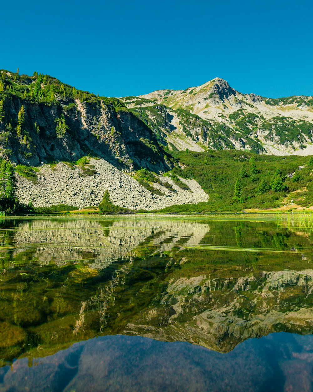 a mountain range is reflected in the still water of a lake