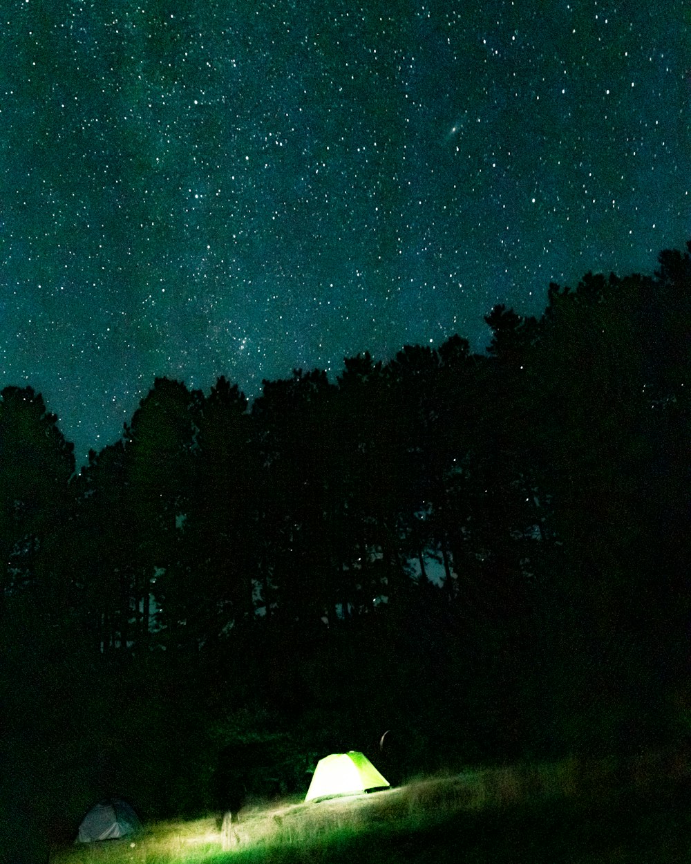 a tent is lit up at night under the stars