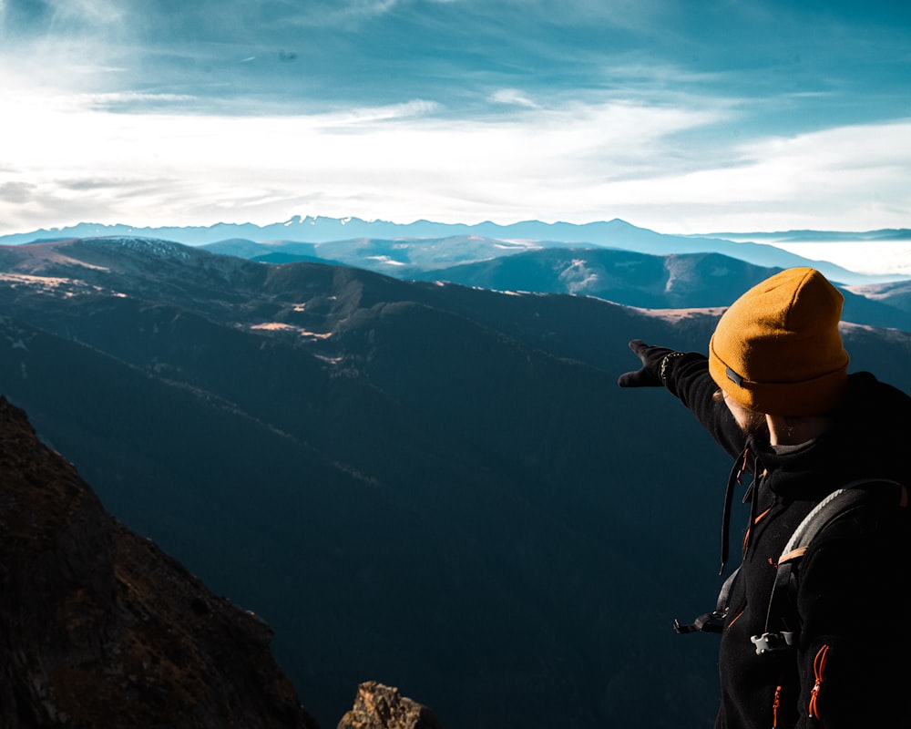 a man standing on top of a mountain pointing at the sky