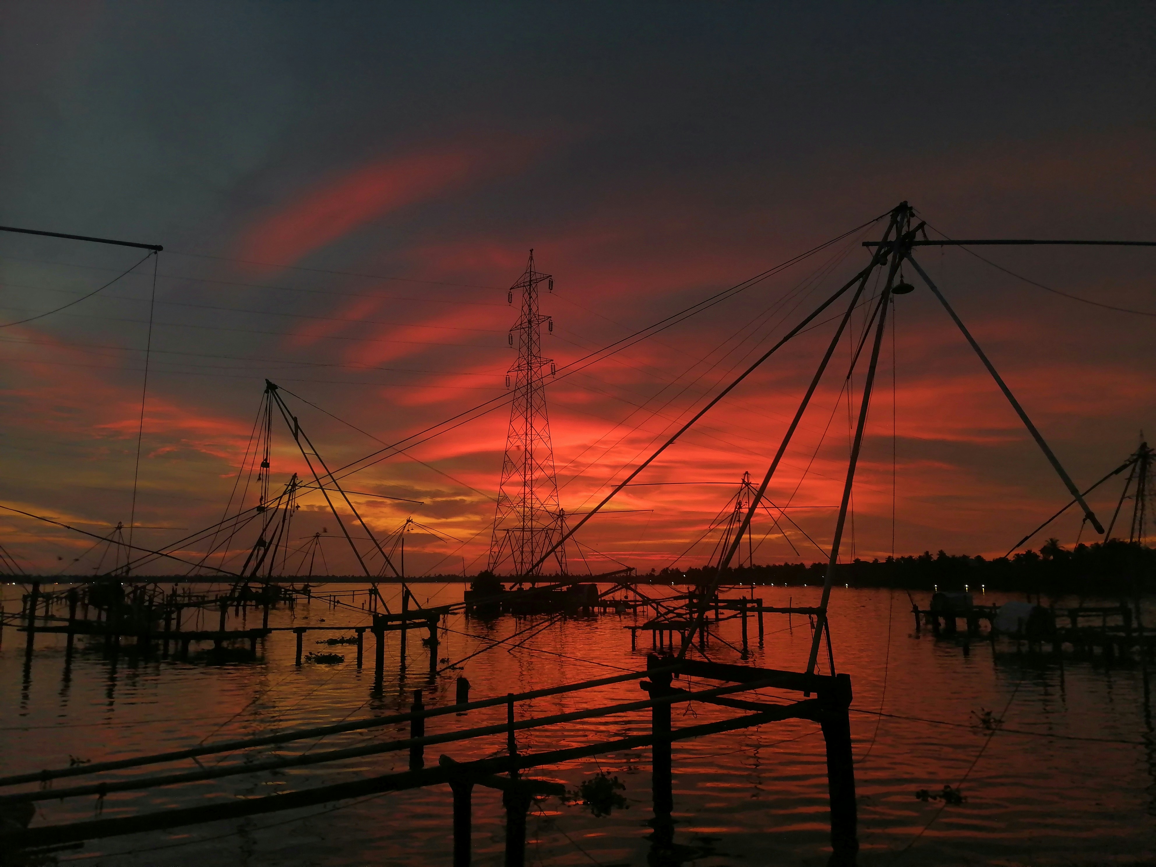 Traditional Kerala fishing nets — Chinese fishing nets at sunset over Alleppey backwaters, silhouetted against orange sky