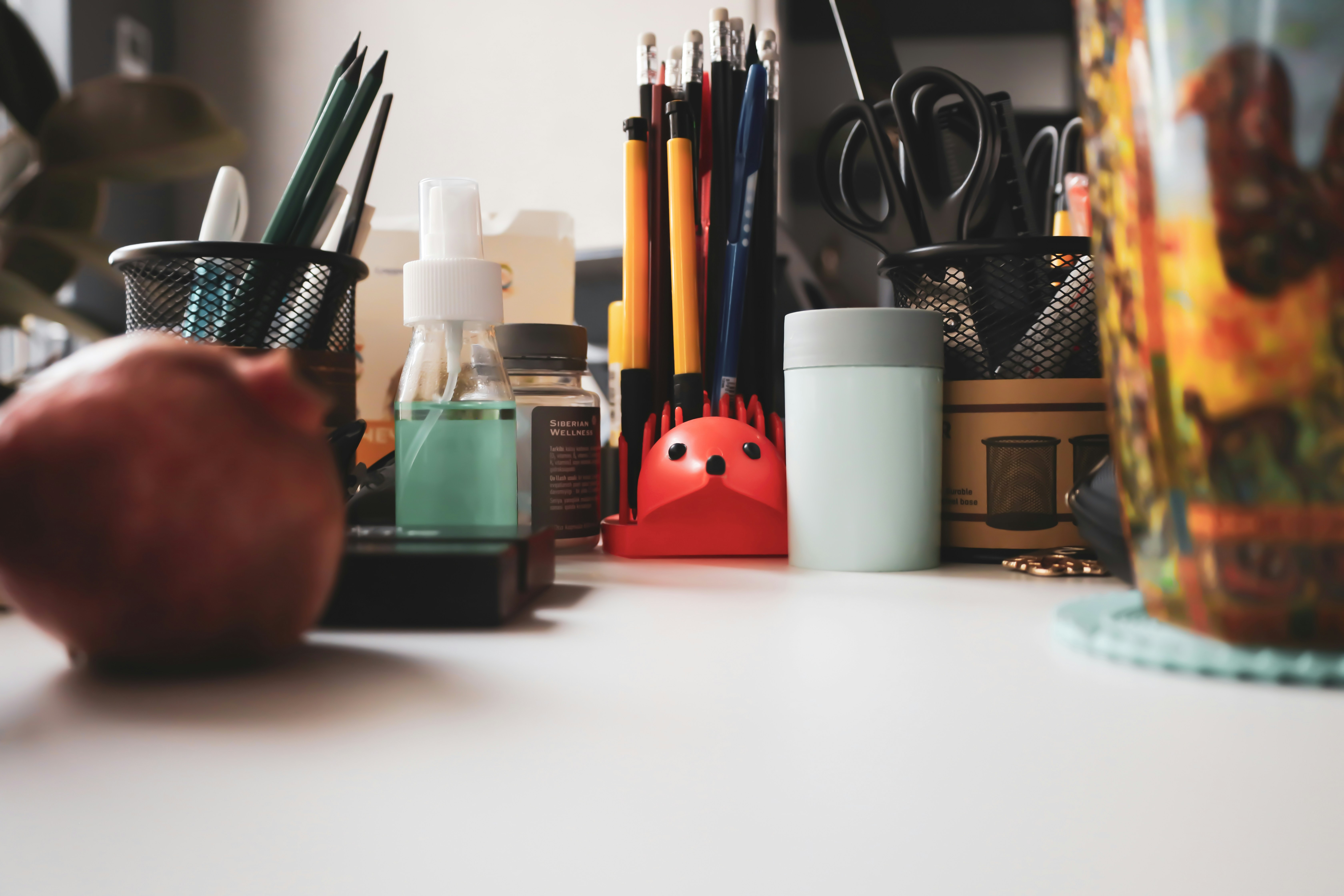 a desk with pens, pencils, and an apple on it