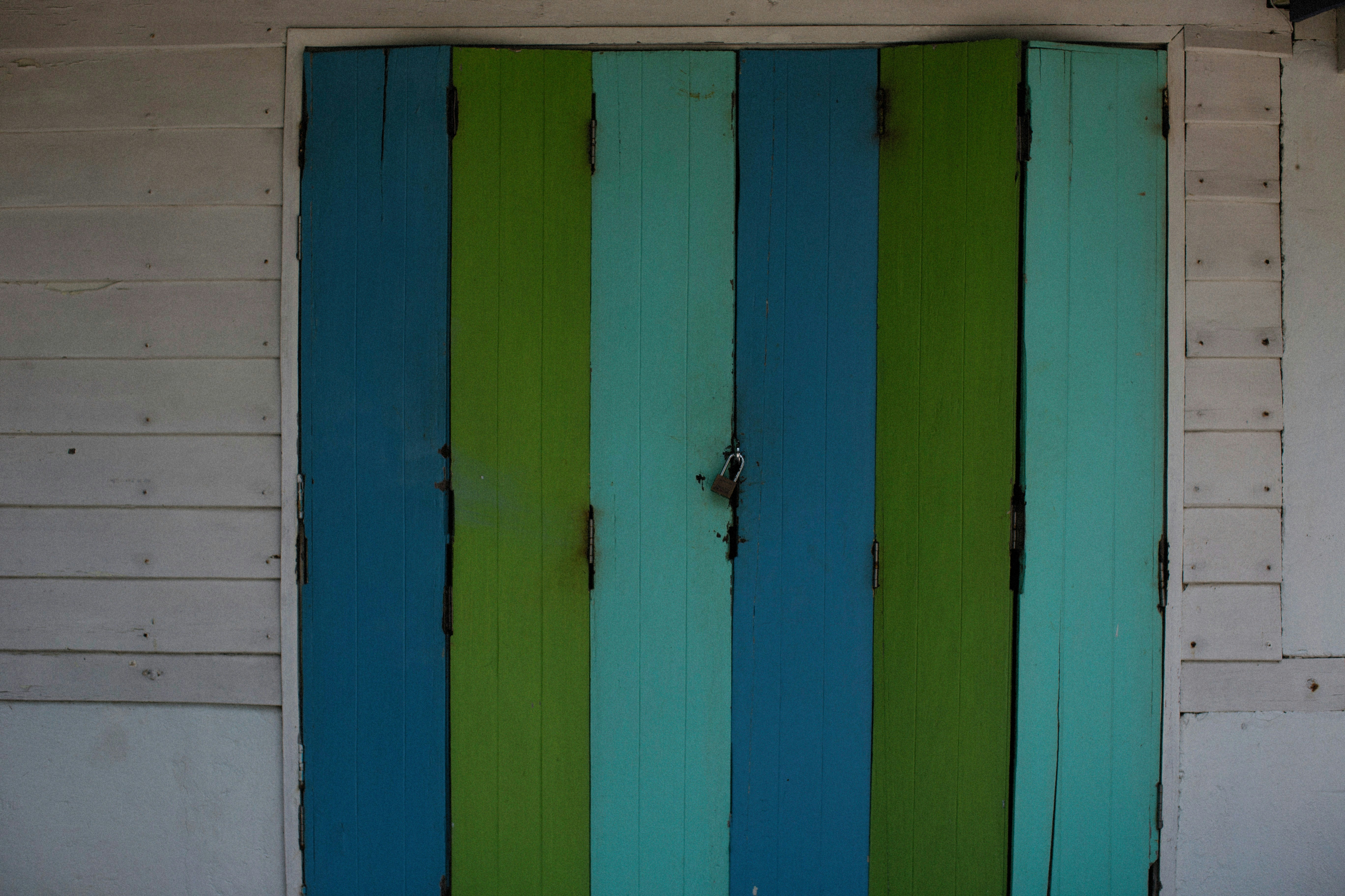 a blue and green striped door on a white building
