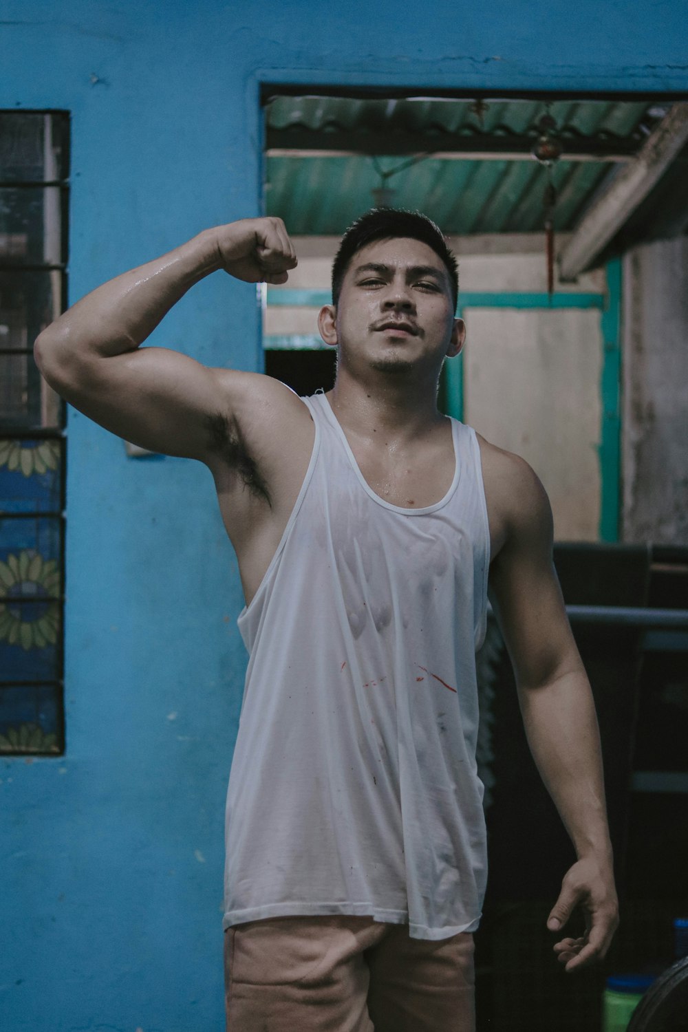 a man standing in front of a blue wall flexing his muscles