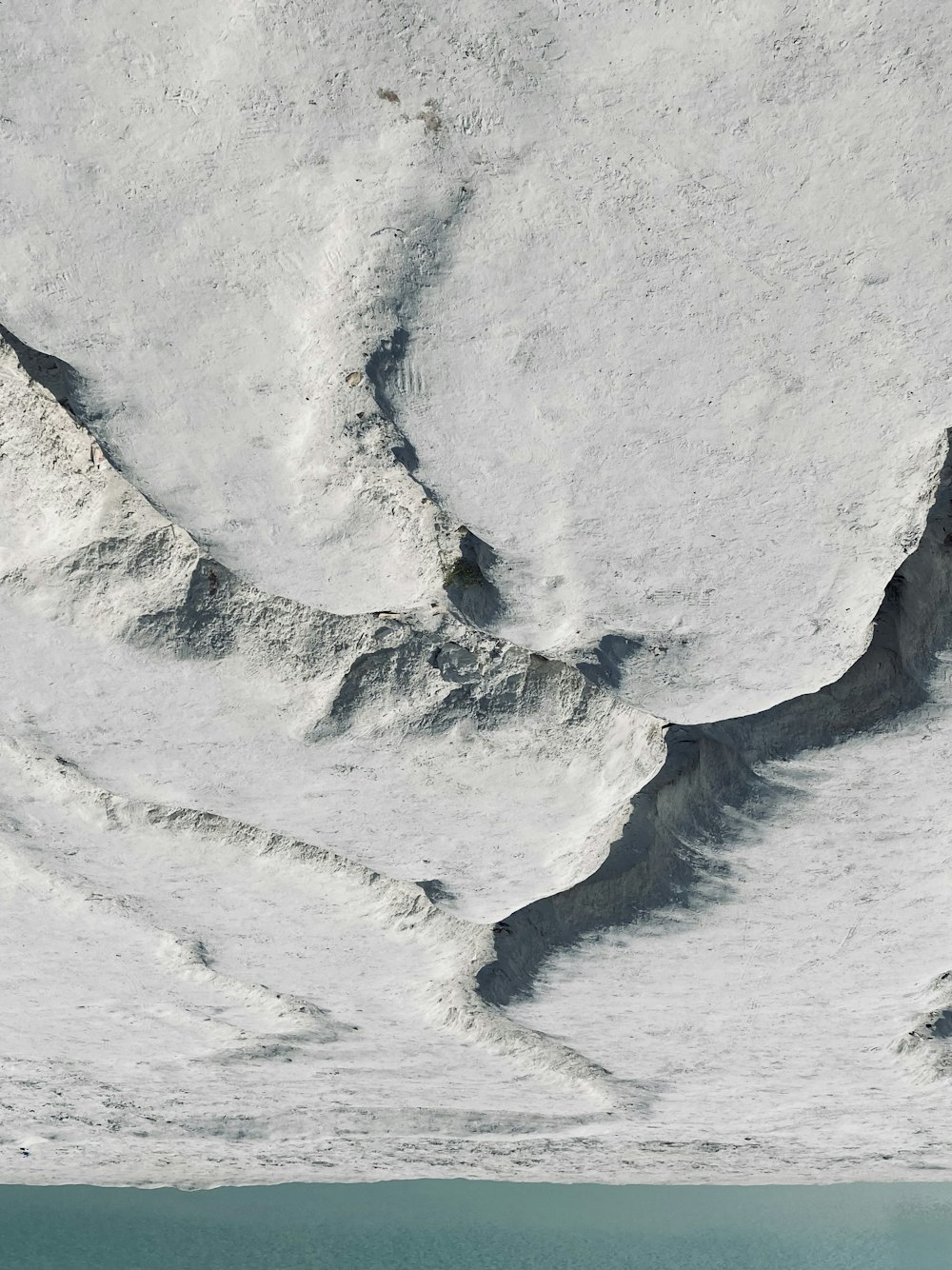 a mountain covered in snow next to a body of water