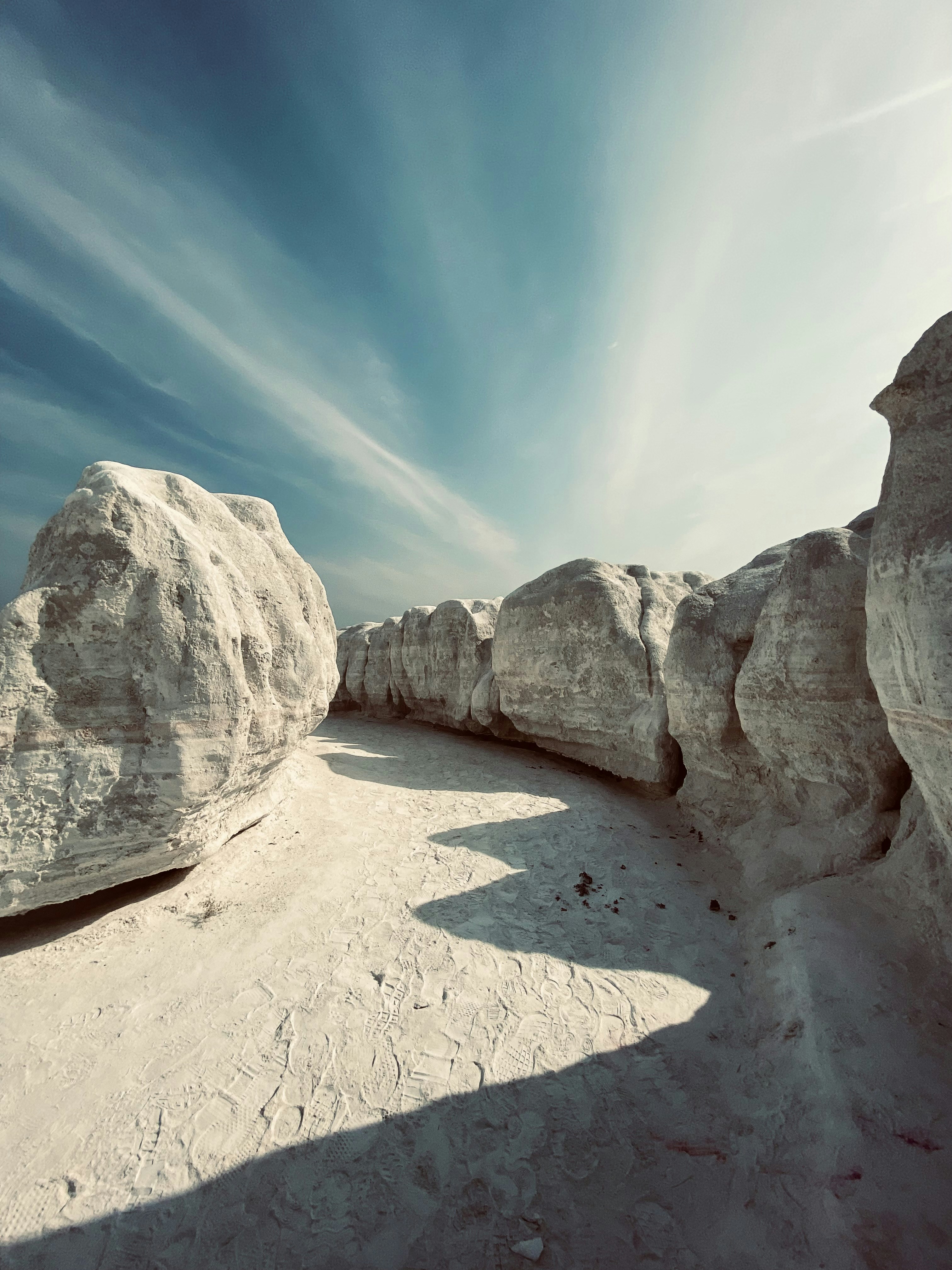 A group of large rocks sitting on top of a sandy beach photo – Free ...