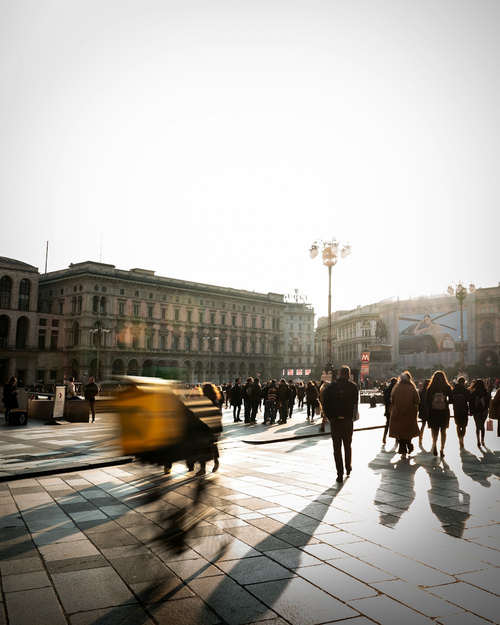 a group of people walking down a street next to tall buildings