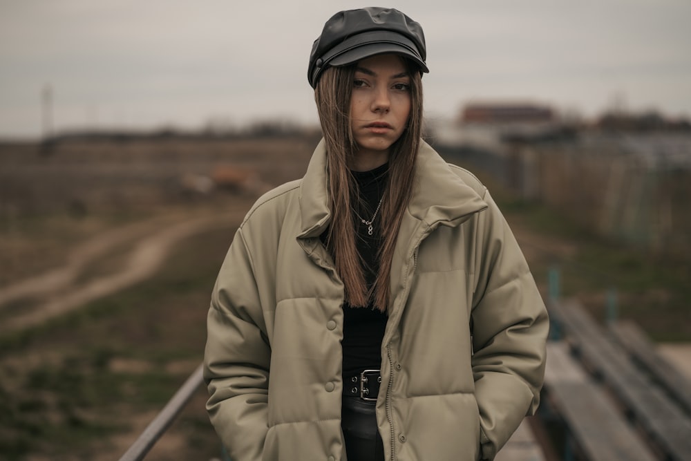 a woman standing on a bridge wearing a hat