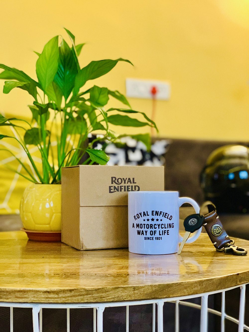 a coffee mug sitting on top of a table next to a plant