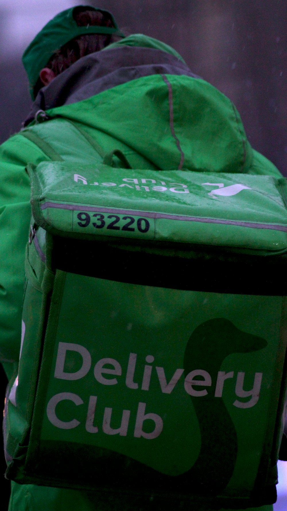 a person in a green jacket carrying a delivery bag