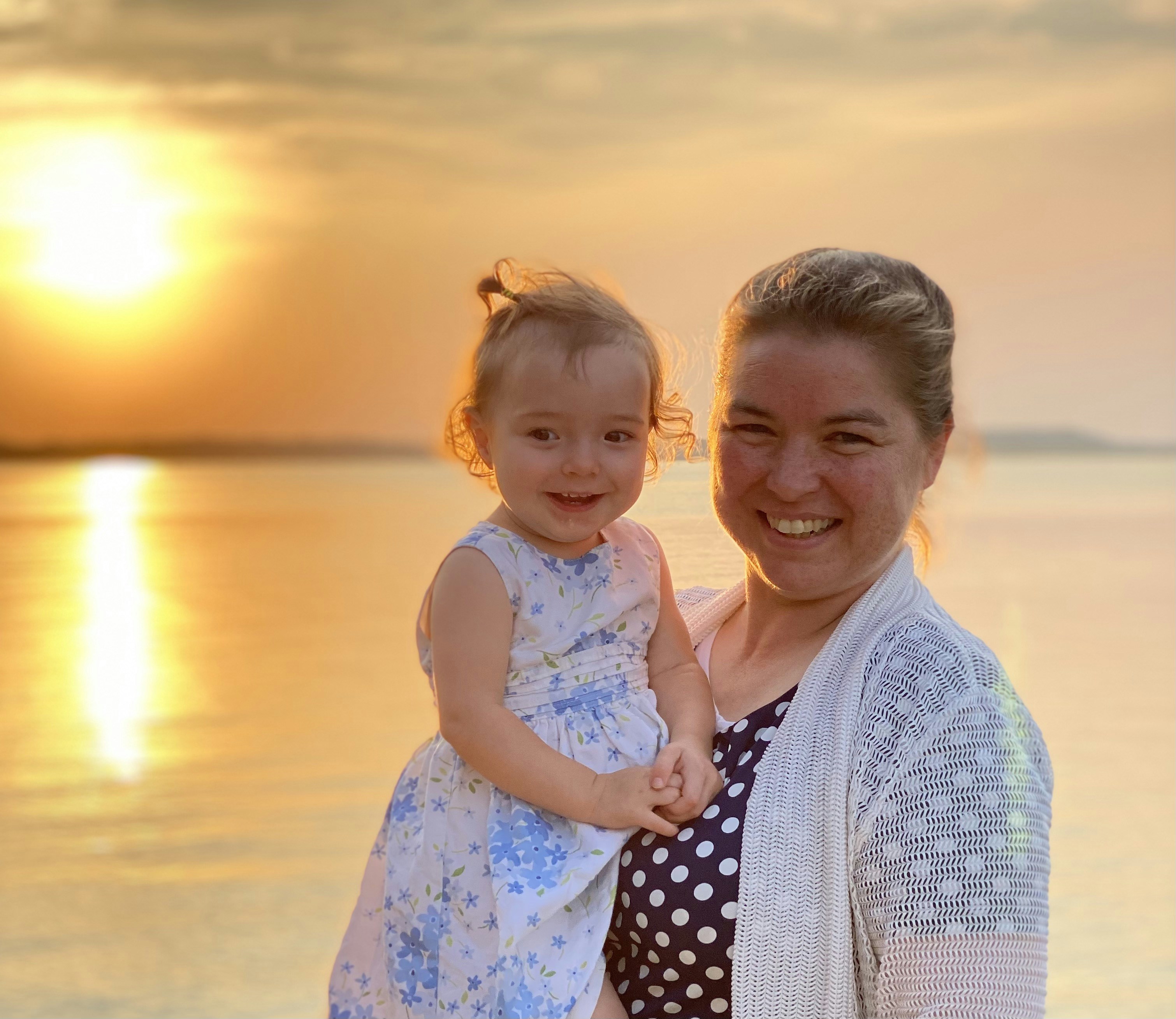 a woman holding a little girl on the beach